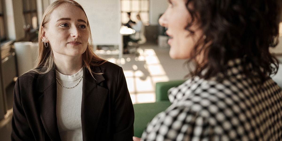 To kvinder snakker i et professionelt kontormiljø